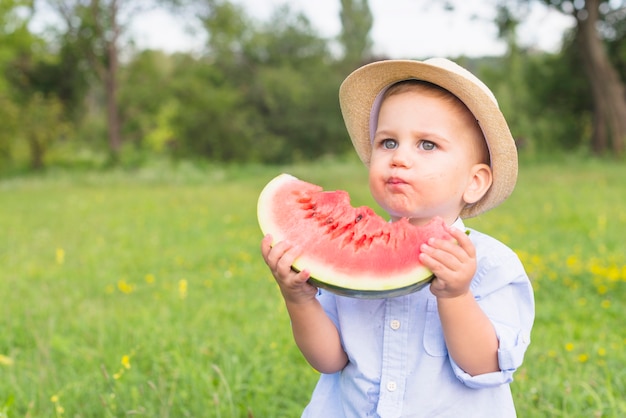 Foto gratuita primer plano de un niño comiendo rebanada de sandía en el parque