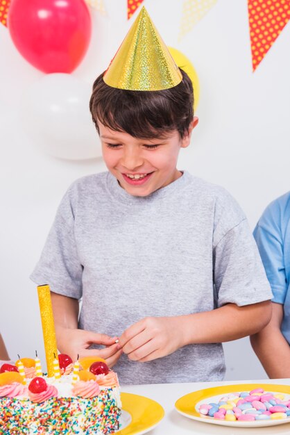 Primer plano de un niño feliz mirando colorido pastel de cumpleaños