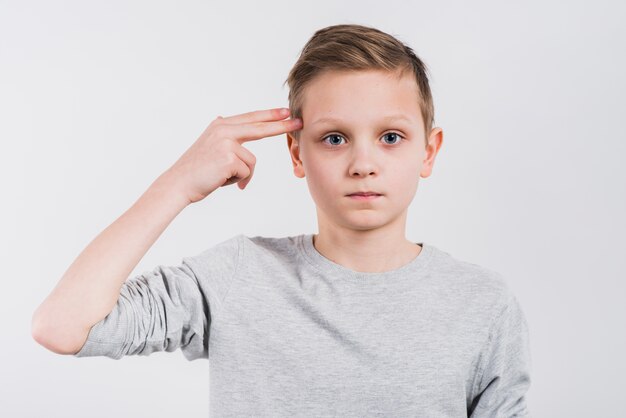 Primer plano de un niño haciendo gesto de pistola o pistola contra el fondo gris