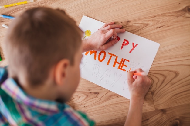 Primer plano de niño preparando un cartel para el día de la madre