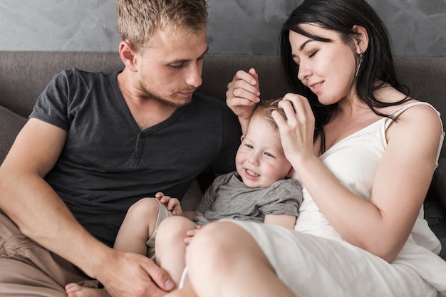 Primer plano de niño sonriente sentado entre sus padres