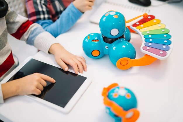 Primer plano de niño tocando la pantalla de la tableta digital en el escritorio blanco