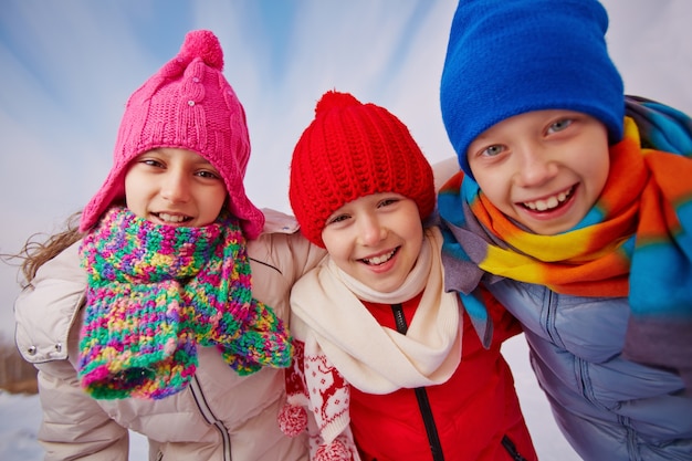 Primer plano de niños felices con gorros de lana y bufandas