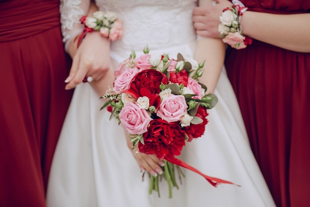 Primer plano de novia sujetando el ramo de boda con las damas de honor