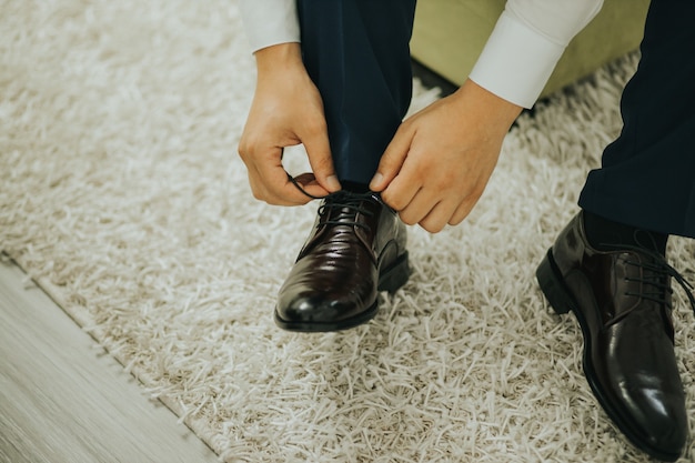 Primer plano del novio arreglando los cordones de los zapatos