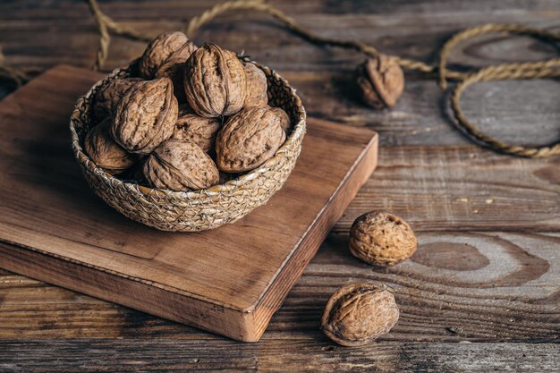 Primer plano de nueces enteras en un recipiente de mimbre sobre un fondo de madera