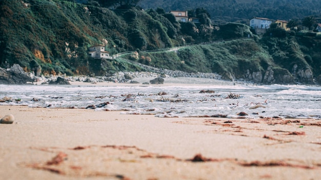 Primer plano de olas de espuma golpeando una orilla de arena en Cantabria, España