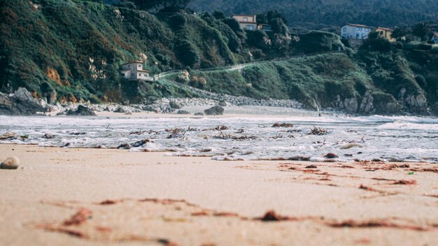 Primer plano de olas de espuma golpeando una orilla de arena en Cantabria, España