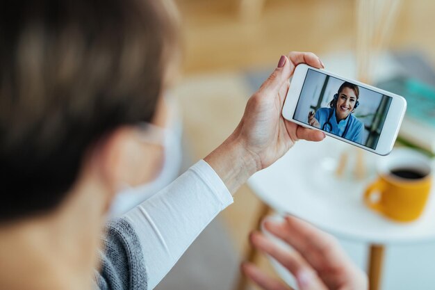 Primer plano de una paciente que usa un teléfono inteligente y tiene una videoconferencia con su médico