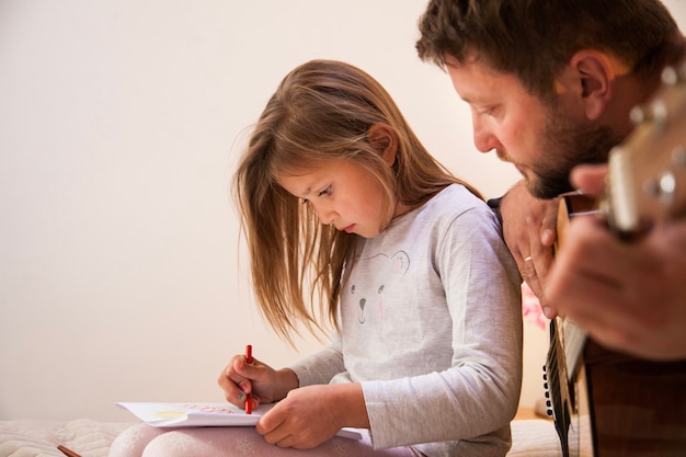 Primer plano de padre mirando a su hija dibujar