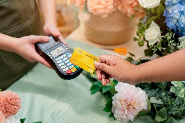 Foto gratuita primer plano de pago fácil con tarjeta de crédito o aplicación de teléfono inteligente trabajadores de invernadero que venden flores en maceta pago sin contacto con el cliente de la tarjeta de crédito en el mostrador mediante el pago sin contacto con código qr