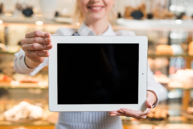 Primer plano de un panadero femenino mostrando tableta digital con pantalla en blanco