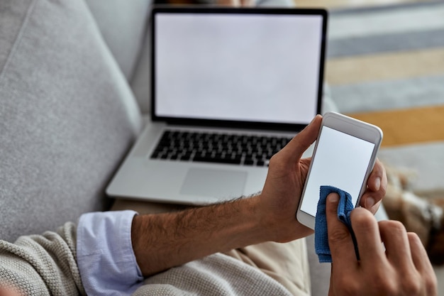 Primer plano de la pantalla de limpieza del hombre en un teléfono inteligente en casa