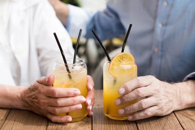 Primer plano par sosteniendo vasos con jugo