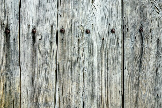 Primer plano de una pared de madera gris con clavos en ella