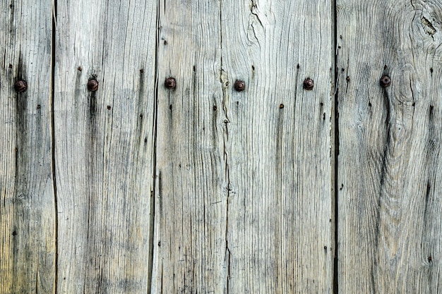 Primer plano de una pared de madera gris con clavos en ella