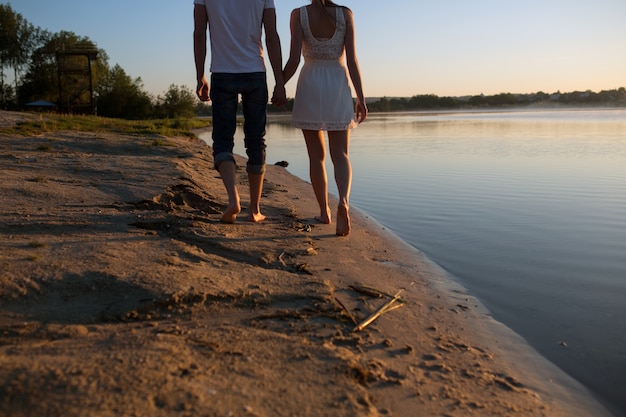 Primer plano de pareja cogidos de la mano con la playa de fondo