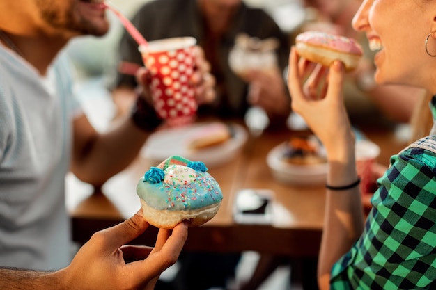 Primer plano de una pareja comiendo donuts glaseados