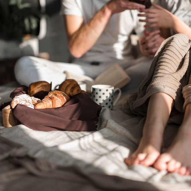 Primer plano de pareja con croissant y café en el desayuno