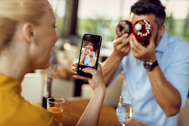 Primer plano de una pareja divirtiéndose con donuts en un café