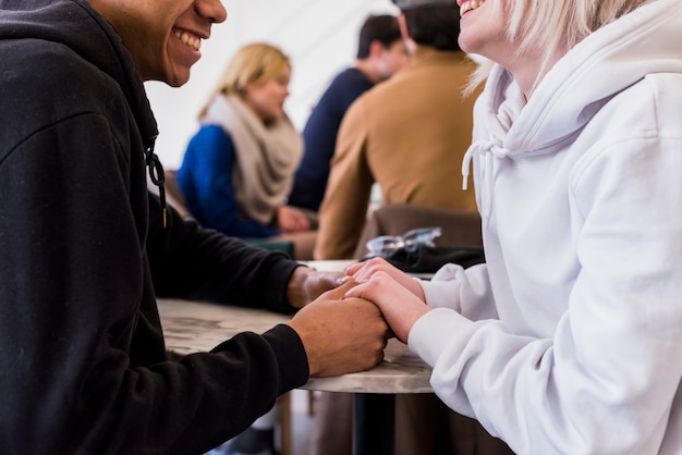 Primer plano de la pareja joven sonriente interracial tomados de la mano