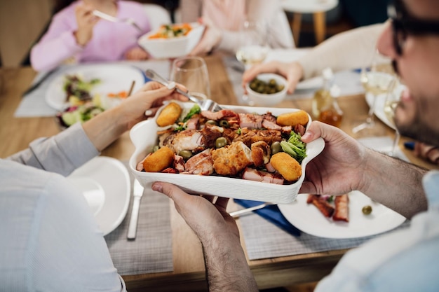 Primer plano de una pareja pasándose comida mientras almuerzan con su familia