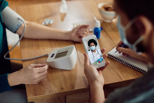 Primer plano de una pareja que mide la presión arterial y hace una videollamada con su médico desde casa