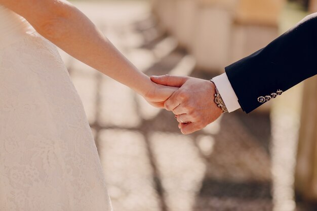 Primer plano de pareja de recién casados cogidos de la mano