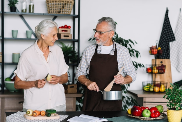Foto gratuita primer plano de pareja senior preparando la comida en la cocina mirando el uno al otro
