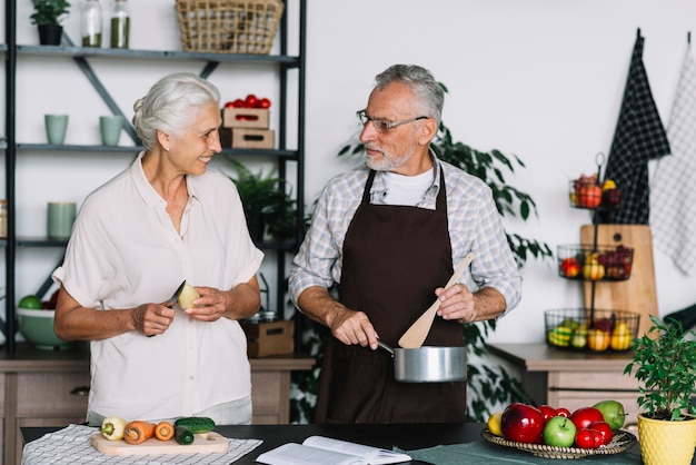 Primer plano de pareja senior preparando la comida en la cocina mirando el uno al otro