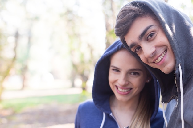 Primer plano de pareja sonriente con sudaderas con capuchas al aire libre