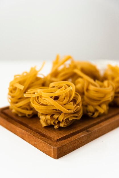 Primer plano de pasta sin cocer tagliatelle sobre tabla para cortar madera