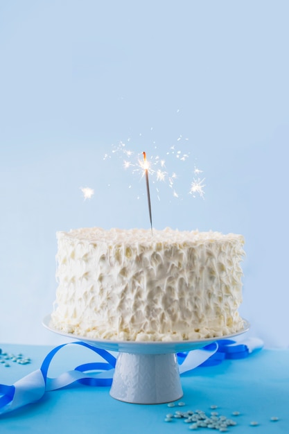 Primer plano de pastel de cumpleaños blanco con bengala ardiente