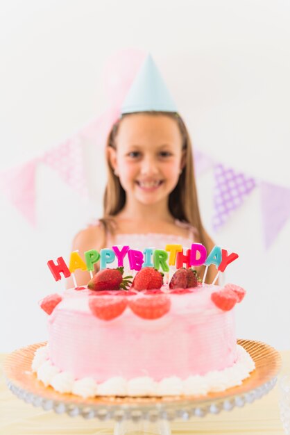 Primer plano de pastel de topping de fresa con coloridas velas de cumpleaños