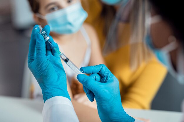 Primer plano de un pediatra que prepara la vacuna para un niño en la clínica médica