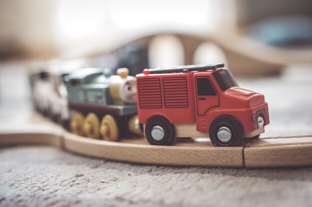 Primer plano de un pequeño coche de juguete en una vía de tren de madera