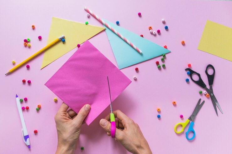 Foto gratuito primer plano de una persona cortando papel con tijera sobre el fondo rosa
