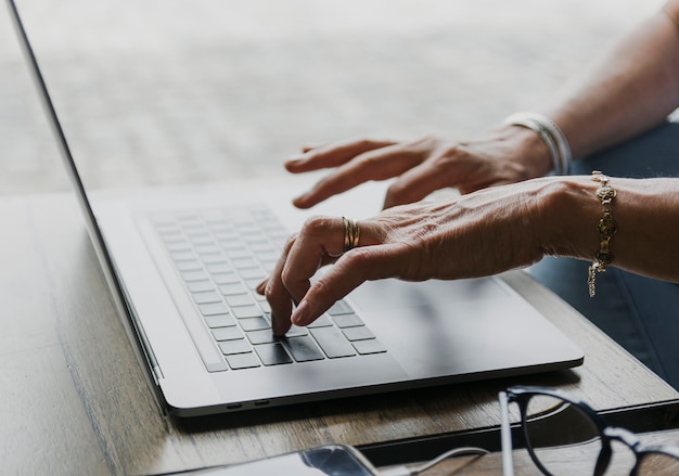 Primer plano de una persona escribiendo en el teclado del portátil