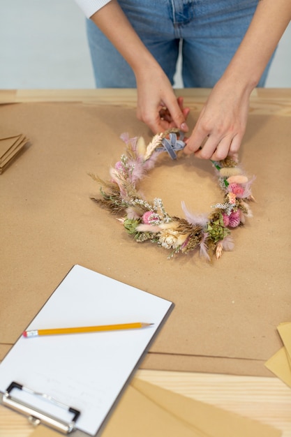 Foto gratuita primer plano persona de negocios creando una corona de flores de alta vista