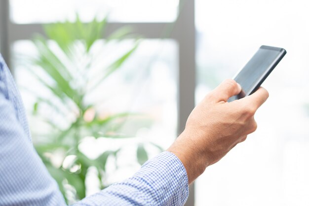 Primer plano de la persona de negocios tocando en la pantalla del teléfono inteligente