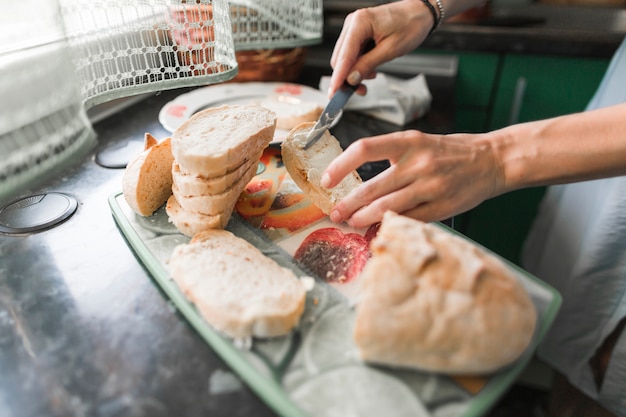 Primer plano de una persona que aplica queso a las rebanadas de pan