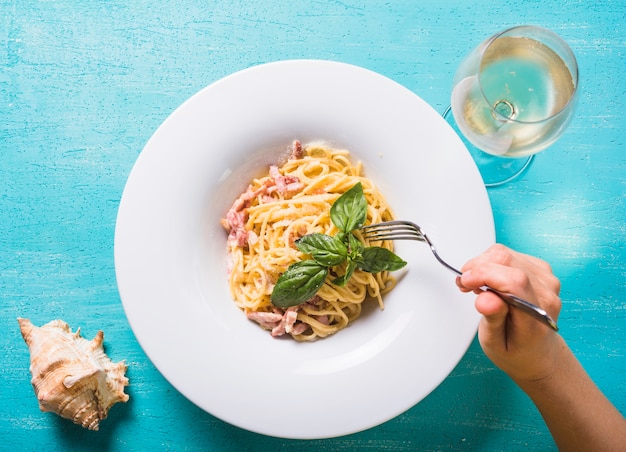Foto gratuita primer plano de una persona que come espaguetis con carne y hojas de albahaca en un plato