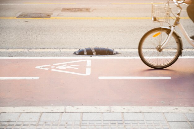 Primer plano de una persona que monta la bicicleta en una carretera con un signo de advertencia de triángulo