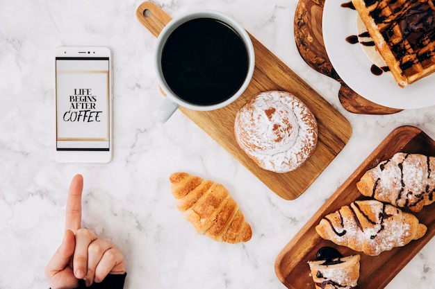 Primer plano de una persona que señala el dedo en el teléfono celular con el mensaje y el desayuno en el telón de fondo con textura de mármol