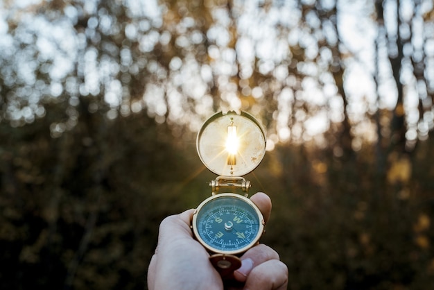 Primer plano de una persona que sostiene una brújula con el sol brillando a través del agujero