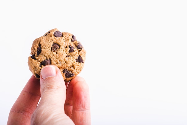 Primer plano de una persona que sostiene una galleta con chispas de chocolate aislada en blanco