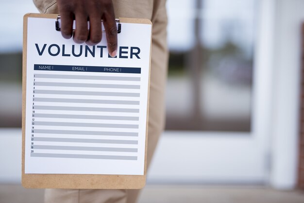 Primer plano de una persona que tiene una hoja de registro de voluntarios