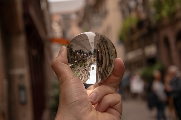 Primer plano de una persona sosteniendo una bola de cristal con el reflejo de edificios históricos