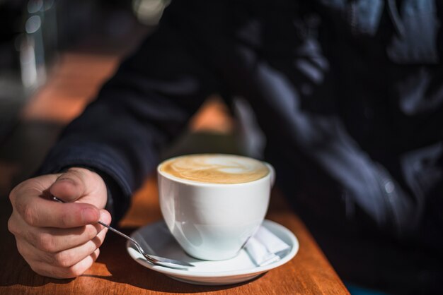 Primer plano de una persona con una taza de café caliente en la mesa