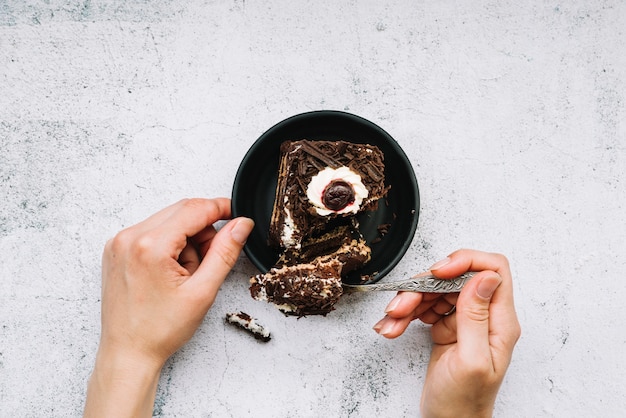 Primer plano de una persona tomando pastel de chocolate con una cuchara sobre fondo grunge